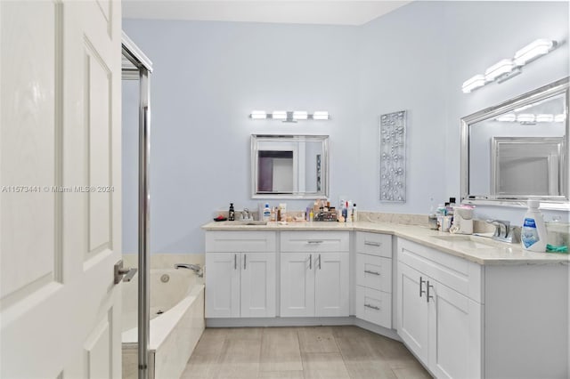 bathroom featuring tiled tub and dual vanity