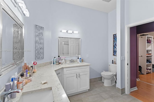 bathroom with toilet, tile flooring, and vanity