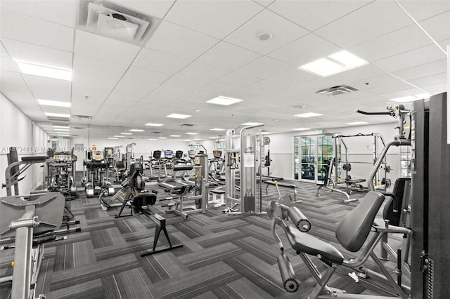 exercise room with a drop ceiling and dark colored carpet