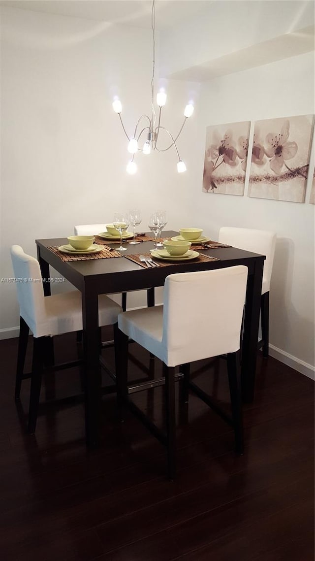 dining area featuring dark wood-type flooring and a notable chandelier