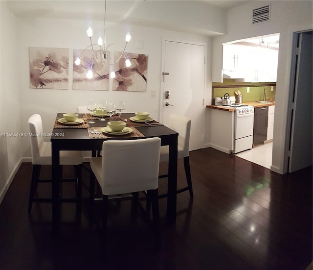 dining space featuring sink, dark hardwood / wood-style floors, and an inviting chandelier