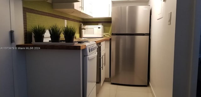 kitchen featuring stainless steel refrigerator, wooden counters, white cabinetry, and light tile floors