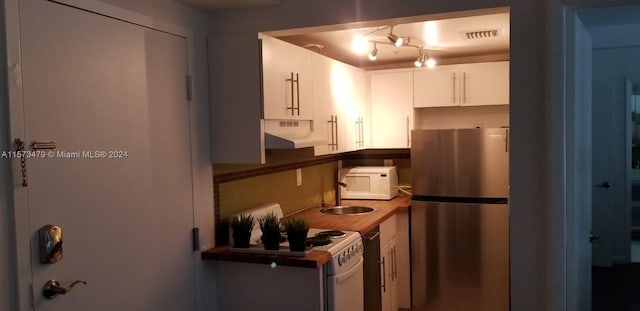 kitchen with white appliances, custom exhaust hood, and white cabinetry