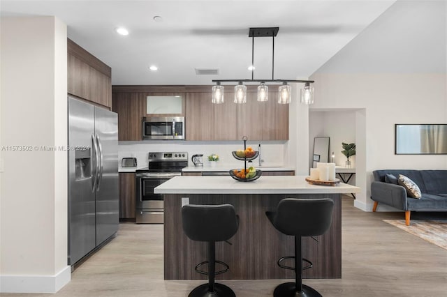 kitchen featuring light hardwood / wood-style flooring, stainless steel appliances, a breakfast bar, and decorative light fixtures