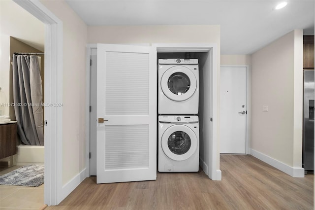 laundry area with light hardwood / wood-style flooring and stacked washing maching and dryer