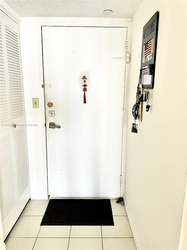 doorway to outside with a textured ceiling and light tile flooring