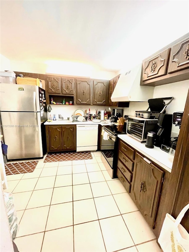 kitchen featuring dark brown cabinets, dishwasher, custom range hood, stainless steel fridge, and light tile floors