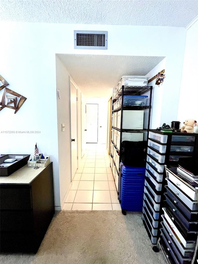 hall featuring a textured ceiling and light tile floors