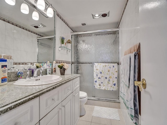 bathroom featuring tile walls, oversized vanity, toilet, an enclosed shower, and tile floors