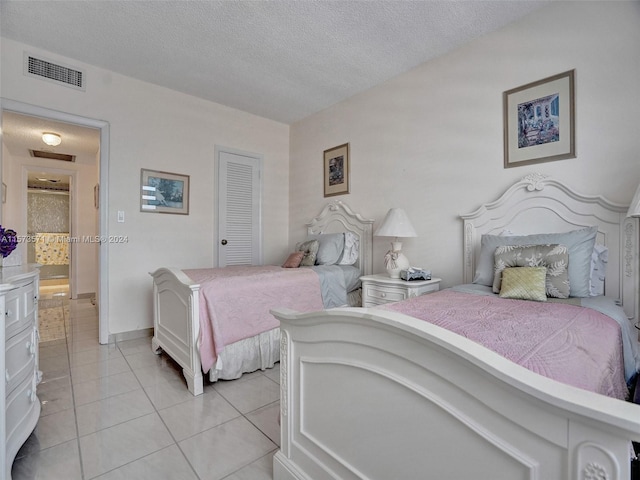 bedroom featuring a textured ceiling and light tile floors