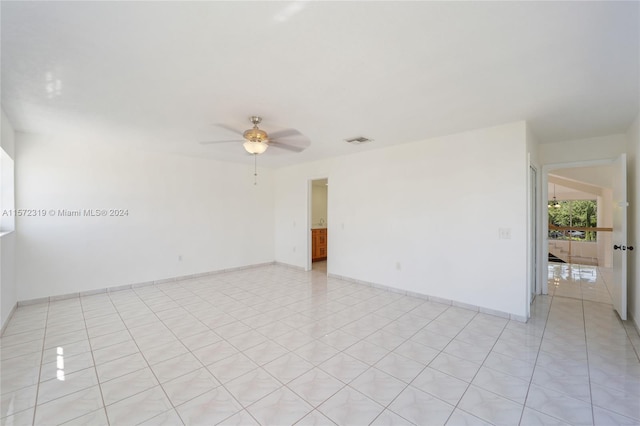 spare room with ceiling fan and light tile floors