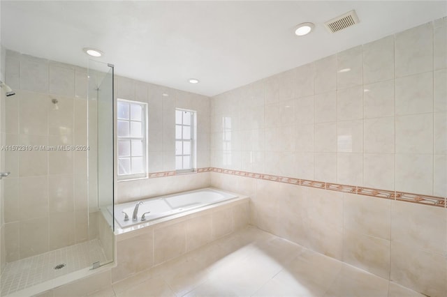 bathroom featuring tile flooring, tile walls, and plus walk in shower