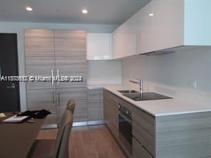 kitchen with dark hardwood / wood-style floors, sink, stainless steel oven, and white cabinetry