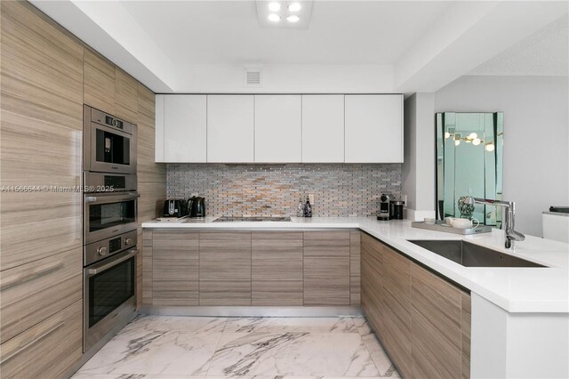 kitchen featuring tasteful backsplash, black electric cooktop, white cabinetry, and sink