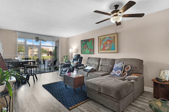 living room featuring ceiling fan, hardwood / wood-style flooring, expansive windows, and a textured ceiling