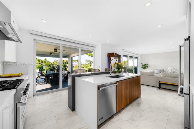 kitchen featuring wall chimney exhaust hood, a kitchen island with sink, sink, light tile floors, and dishwasher