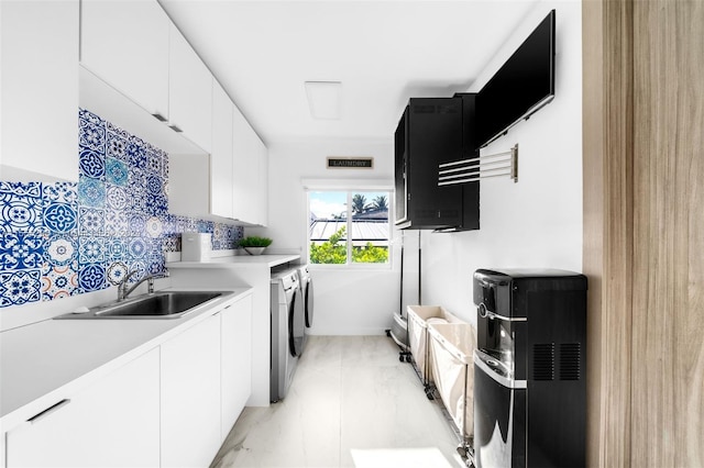 kitchen with washer and dryer, light tile floors, white cabinets, sink, and tasteful backsplash