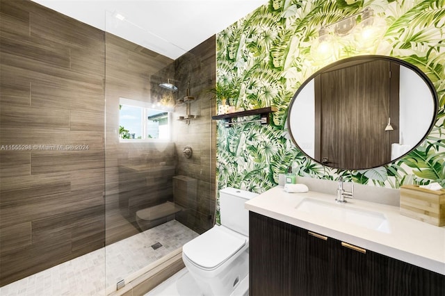 bathroom with tiled shower, vanity, and toilet