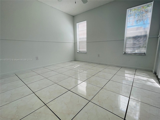 tiled spare room featuring a textured ceiling and ceiling fan