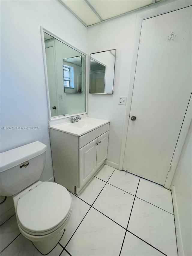 bathroom with tile flooring, vanity, and toilet