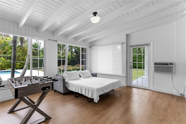 sunroom / solarium with a healthy amount of sunlight, a wall mounted AC, and beam ceiling