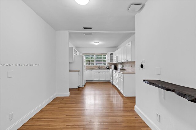 kitchen featuring sink, tasteful backsplash, light wood-type flooring, and white cabinetry