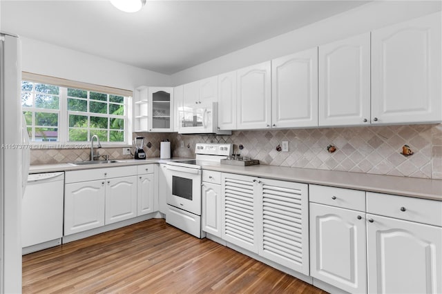 kitchen with white appliances, light wood-type flooring, white cabinetry, backsplash, and sink