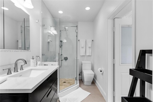 bathroom featuring a shower with shower door, toilet, tile floors, and large vanity