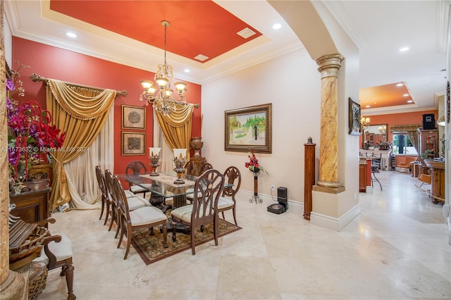 dining room with ornate columns, a raised ceiling, tile floors, a chandelier, and ornamental molding