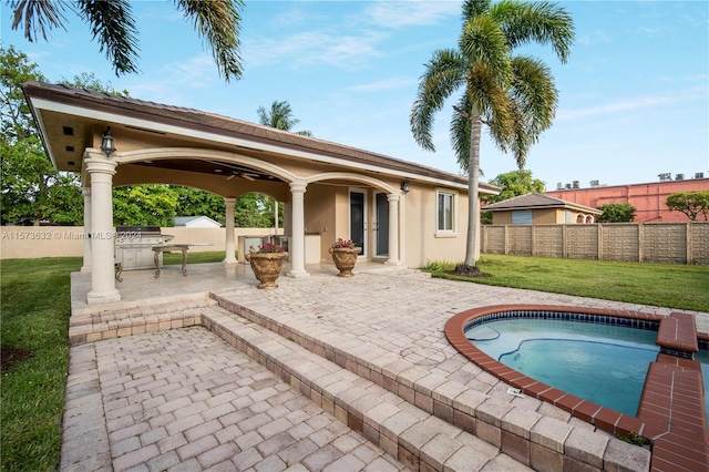 view of swimming pool featuring a lawn, ceiling fan, and a patio