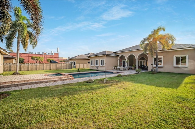 exterior space featuring a patio area, a swimming pool with hot tub, and a yard