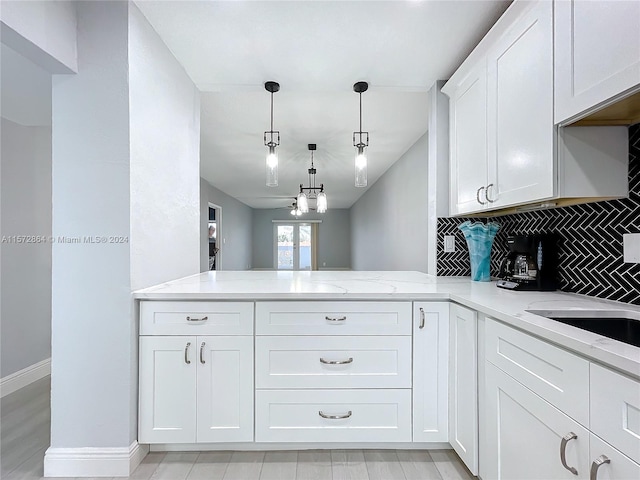 kitchen featuring pendant lighting, white cabinetry, light stone counters, tasteful backsplash, and kitchen peninsula