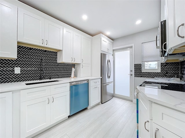 kitchen featuring white cabinetry, sink, light stone countertops, and appliances with stainless steel finishes