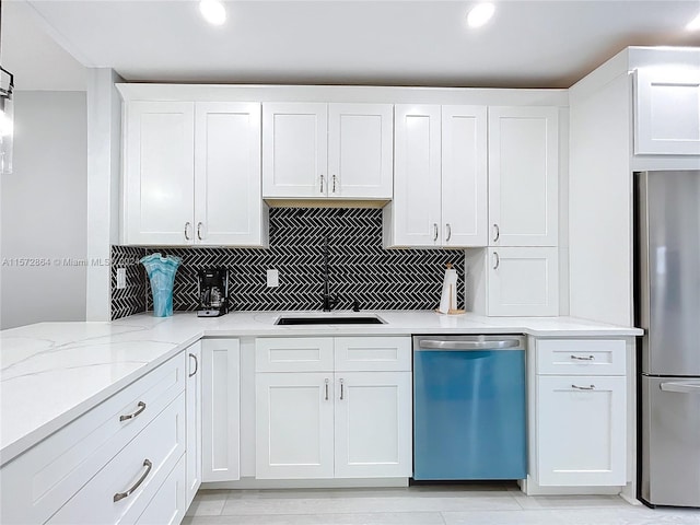 kitchen featuring stainless steel appliances, light stone countertops, white cabinetry, sink, and decorative backsplash