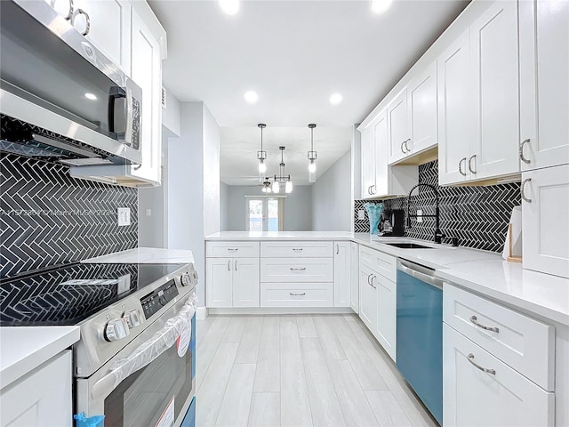 kitchen with sink, white cabinetry, decorative light fixtures, appliances with stainless steel finishes, and backsplash