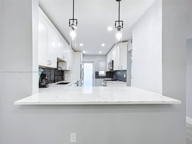 kitchen with pendant lighting, light stone counters, and kitchen peninsula