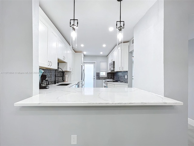 kitchen featuring pendant lighting, white cabinetry, kitchen peninsula, and appliances with stainless steel finishes