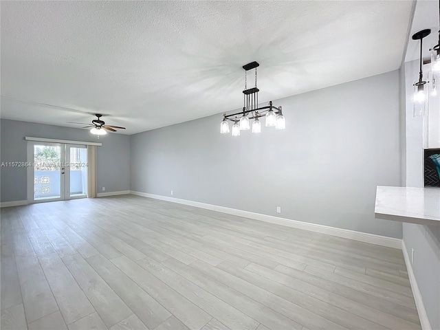 interior space with light wood-type flooring, french doors, a textured ceiling, and ceiling fan with notable chandelier