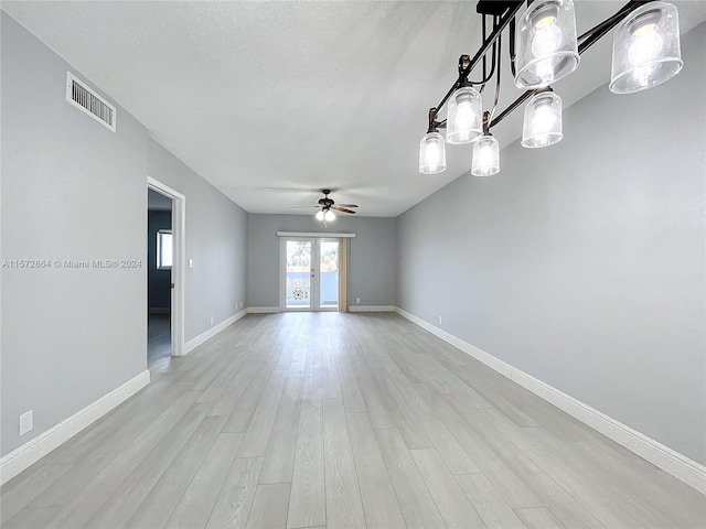 spare room with ceiling fan, light wood-type flooring, french doors, and a textured ceiling