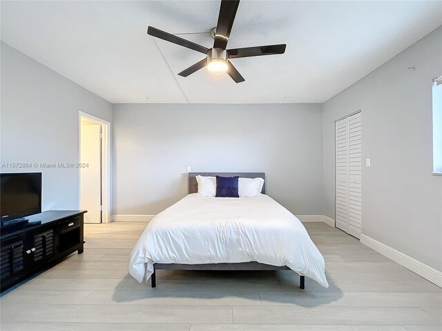 bedroom featuring ceiling fan, light hardwood / wood-style floors, and a closet