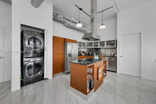 kitchen with appliances with stainless steel finishes, stacked washer / dryer, a kitchen island, light tile flooring, and a high ceiling