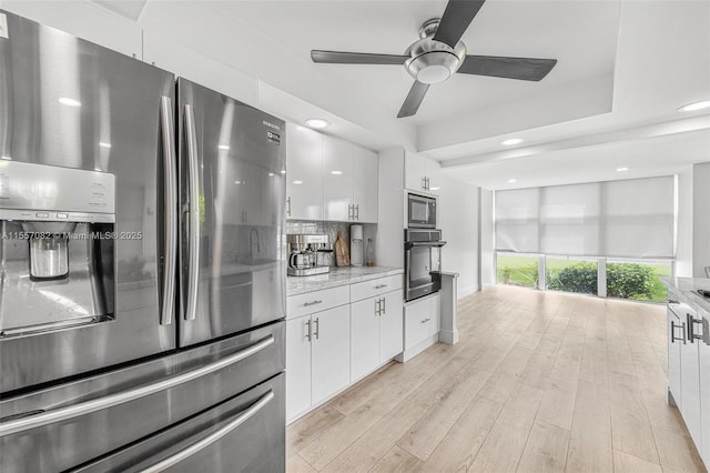 kitchen featuring white cabinets, oven, decorative backsplash, stainless steel fridge, and built in microwave