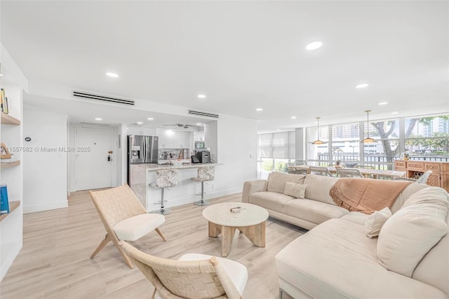 living room with light hardwood / wood-style floors and a wall of windows