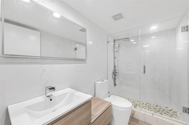 bathroom featuring vanity, a shower with shower door, tile walls, and toilet