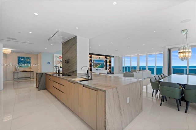 kitchen featuring light tile floors, a notable chandelier, hanging light fixtures, a wall of windows, and light stone countertops