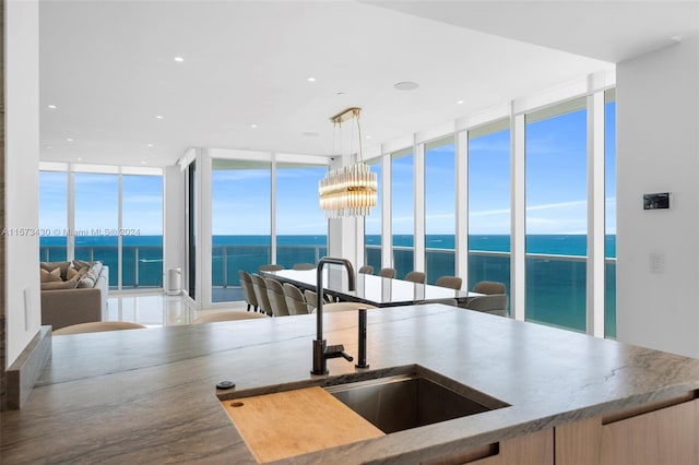 kitchen with an inviting chandelier, hanging light fixtures, a wall of windows, and a water view