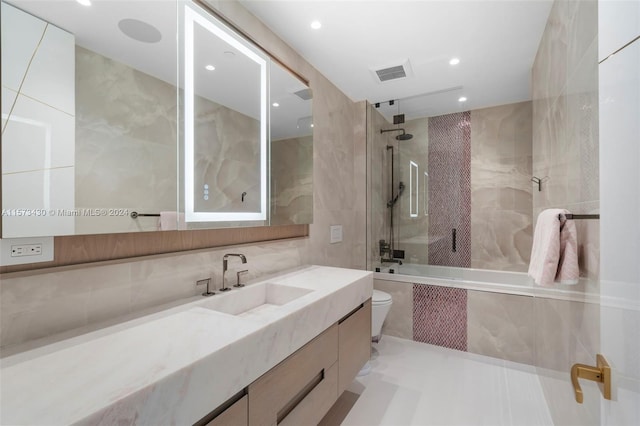 bathroom with toilet, tile walls, and large vanity