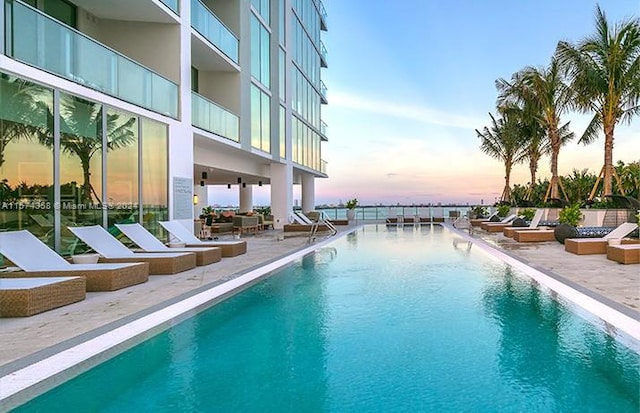 pool at dusk with a patio area