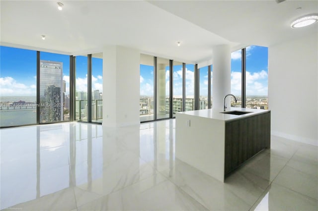 kitchen with floor to ceiling windows, light tile floors, and sink