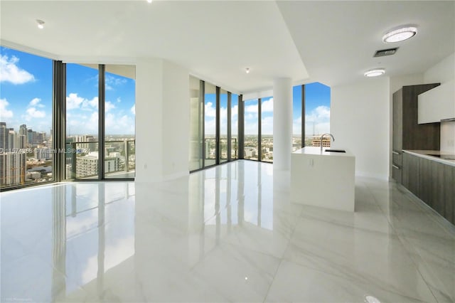 empty room with sink, expansive windows, light tile flooring, and a wealth of natural light